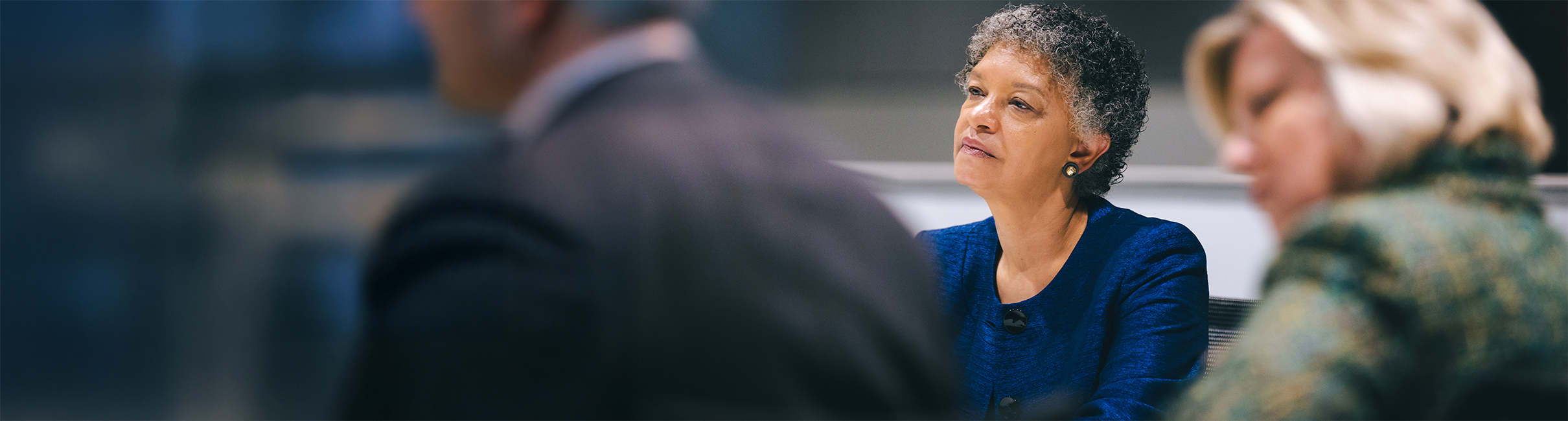 An image of Susan M. Collins listening to speakers at a table.