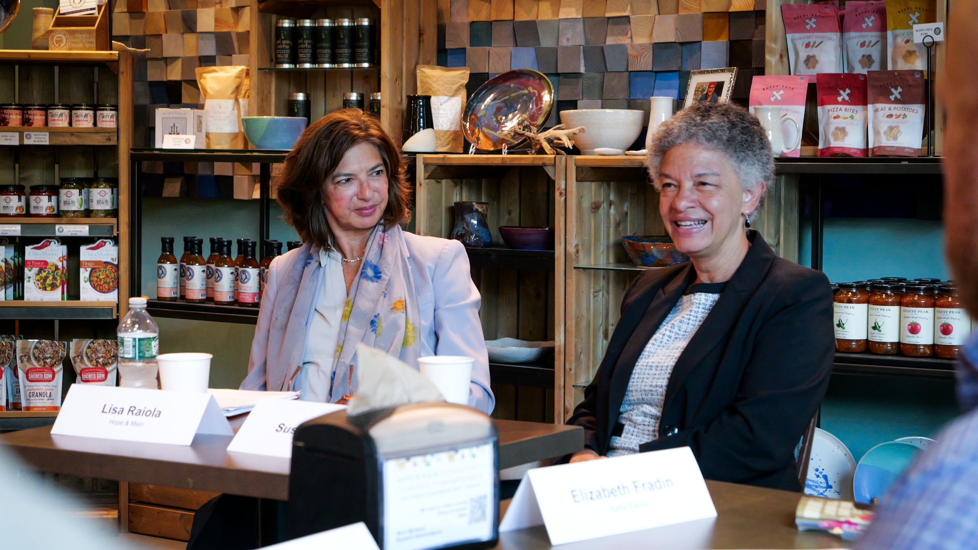 A photograph of Susan M. Collins, President and CEO of the Boston Fed, talking and smiling at the small business owners discussionat Hope & Main.